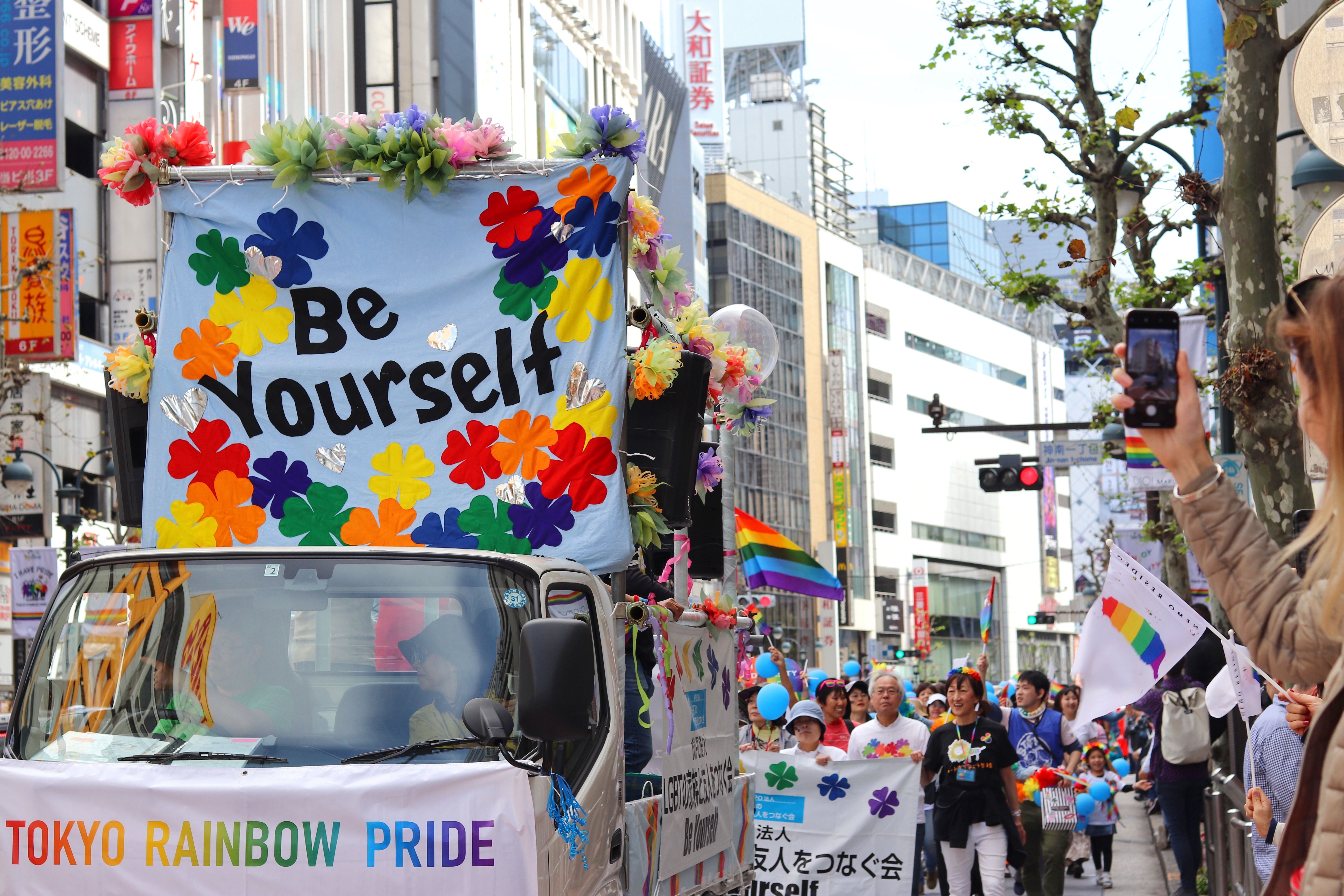 A colorful Tokyo Rainbow Pride parade with a Be Yourself banner