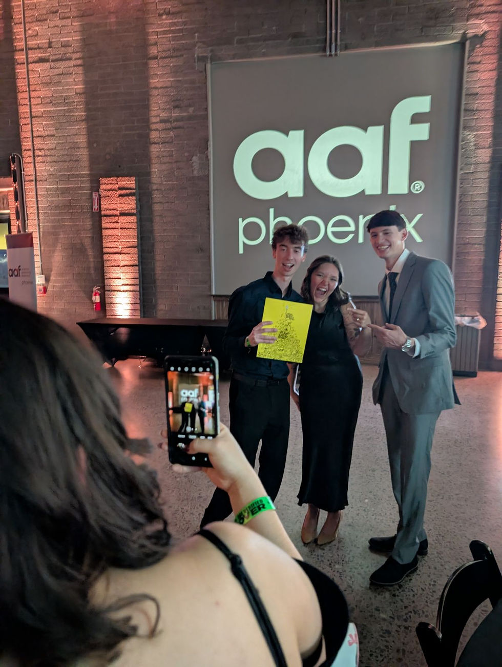 girl taking pictures of three friends at awards show