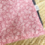 Close-up of pink floral waterproof picnic blanket with delicate cotton print and protective navy PU backing.