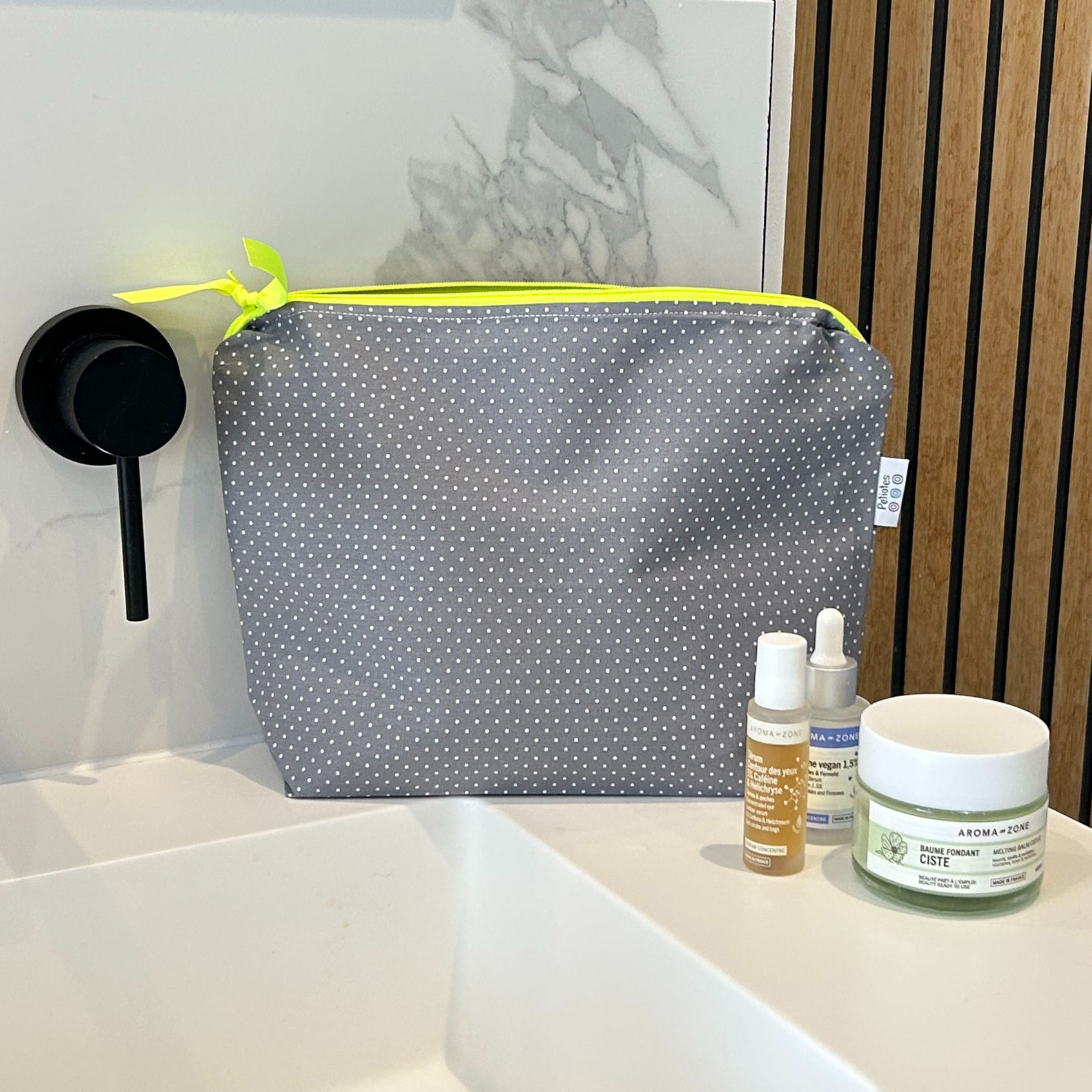 Grey polka dot waterproof wash bag styled with skincare products — handcrafted by Petiotes London
