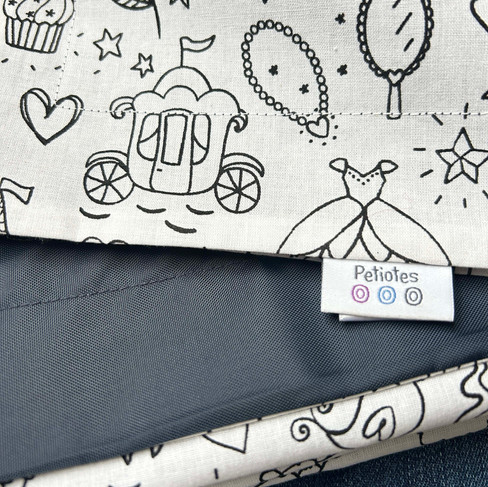 Close-up of Petiotes colouring picnic blanket — 100% cotton fabric with waterproof navy backing and Petiotes label