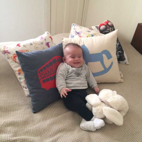 Thumbnail: Personalised London bus cushion in navy cotton with baby in nursery, handcrafted in London — Petiotes