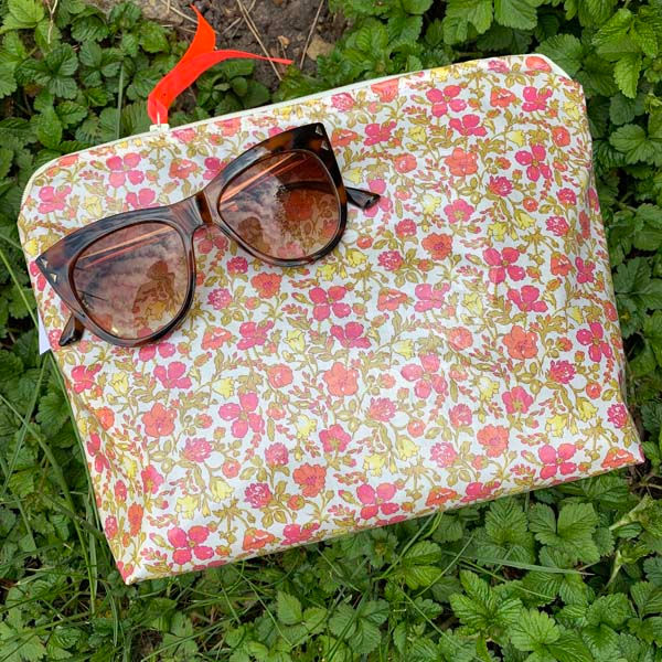 Thumbnail: Compact Petiotes wash bag with a custom "C" initial, made from coated Liberty meadow fabric with pink and yellow flowers