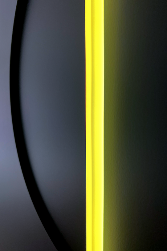 Close-up of acrylic rod in black deepened circle with yellow colored light.