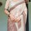 Thumbnail: Close-up of a premium beige linen saree showcasing a subtle floral print and an intricate ethnic patterned pallu.