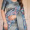 Thumbnail: Close-up of a premium blue silk saree showing the vibrant pink and white floral print with a wide zari border