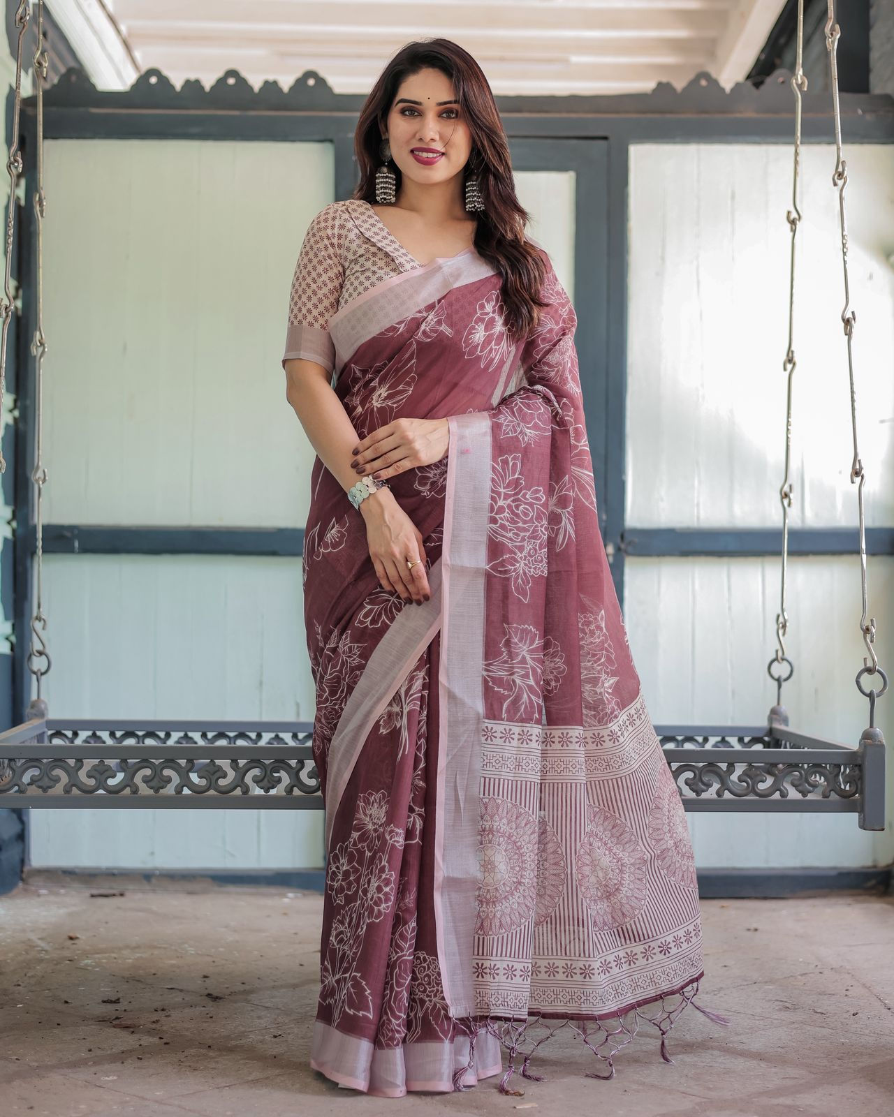 Woman in a Maroon Linen Saree with white floral print and a detailed woven border. Lightweight everyday saree.