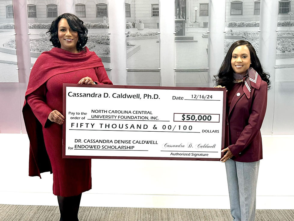 Two adults in red attire holding a large ceremonial check