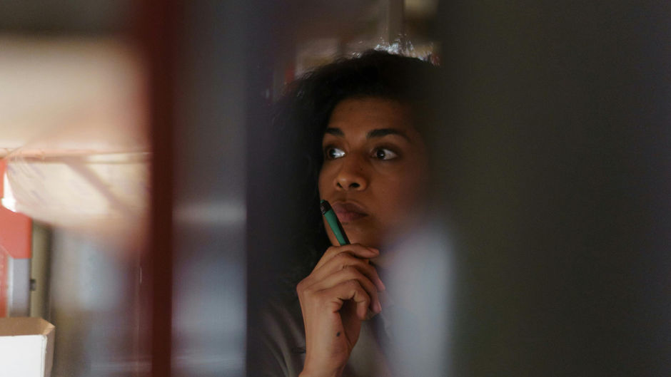 Woman in a dimly lit room in deep thought.