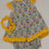 Thumbnail: Front view of dress and bloomers.  Floral Pattern with pink, yellow, and green colors. Yellow trim with polka dots.