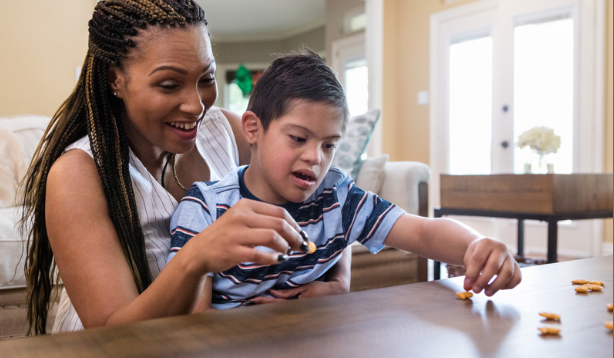 Woman playing with goldfish on a coffee table with a boy who has special needs