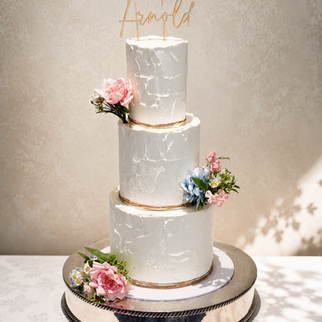 Elegant three-tier textured buttercream wedding cake with blush pink and blue florals at Blunsdon House Hotel in Wiltshire.