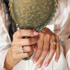 Woman holding a vintage mirror while wearing Calanthe marquise and Allora pear-cut lab-grown diamond engagement rings.