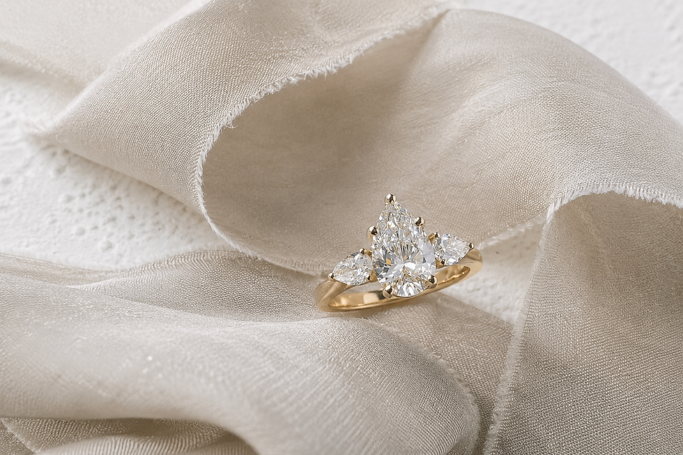 Pear shaped three stone diamond engagement ring on soft neutral fabric background