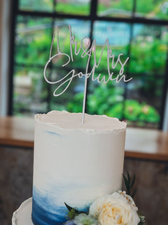 Two-tier ombré blue wedding cake with white and yellow fresh flowers, displayed at The Pear Tree wedding venue