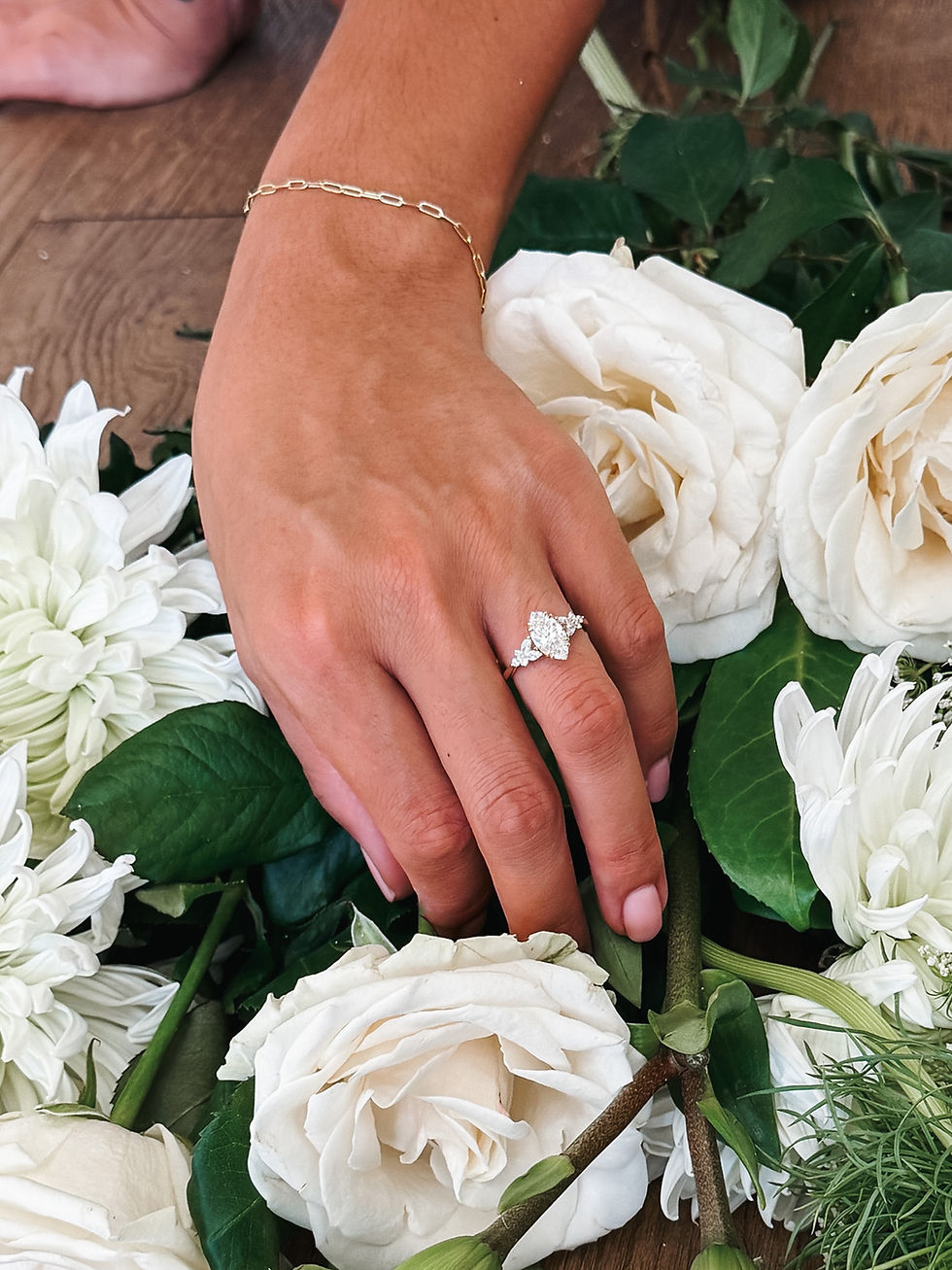 Thumbnail: Calanthe marquise diamond engagement ring photographed among white flowers