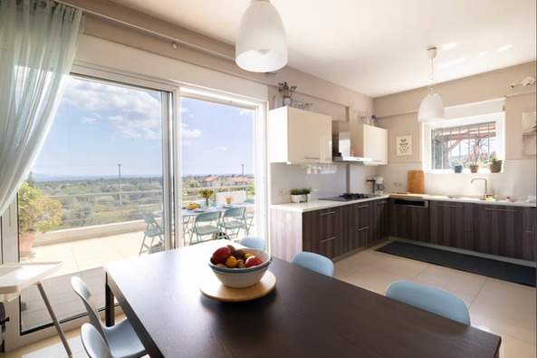 Bright fully equipped kitchen at Villa Abelos Christina with indoor dining area and terrace overlooking the Attica Coast.
