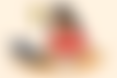 Ilustração colorida em estilo simples e criativo, com contornos finos em preto e fundo claro. Mostra uma mulher de cabelos escuros sentada à mesa, olhando animada para um papel à sua frente. No papel há uma lista com vários X vermelhos e um item final marcado com um check verde. Acima da cabeça da mulher, uma lâmpada acesa simboliza uma ideia ou descoberta. Um laptop está sobre a mesa, e o ambiente transmite leveza e criatividade.