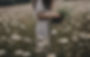 a woman with dark wavy hair not looking at the camera, picking flowers in a field_edited.j