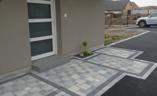 Porte d'entrée avec marche-bloc et sol en pavés et enrobés à chaud noir