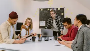 cinco jovens numa mesa olhando para o tablet