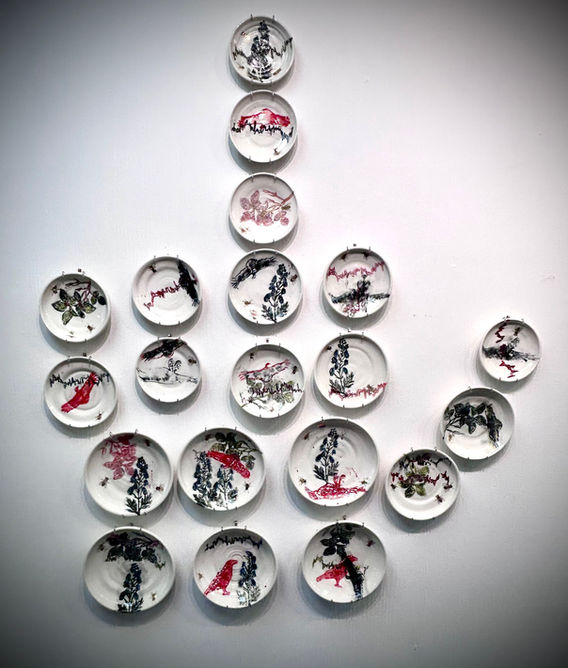 20 block printed plates arranged in a middle finger silhouette  with imagery of crows, panic attack ekg, monkshood flowers, poison ivy, vultures, and golden flies.  