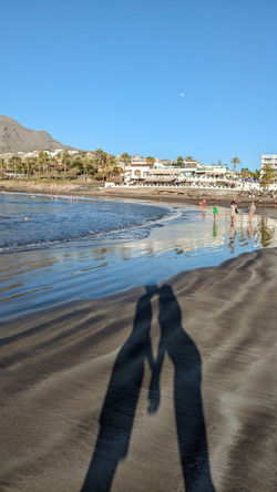 playa de arena negra en Tenerife con la sombra de una pareja besándose