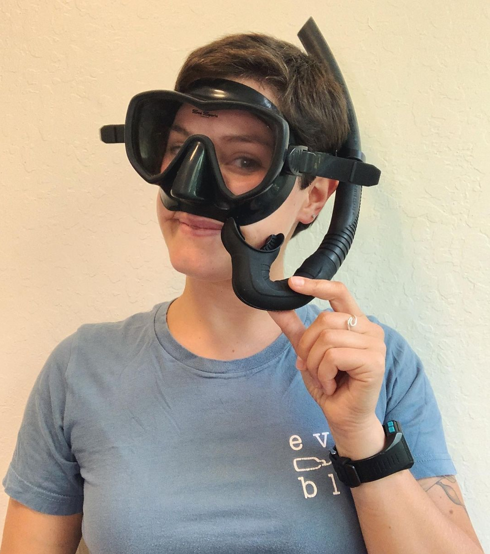 Everblue team member Ellie wears a mask and snorkel and smiles at the camera.