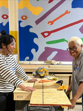 Black woman standing confidently in a styled workspace with power tools, representing creativity, craftsmanship, and intentional living.