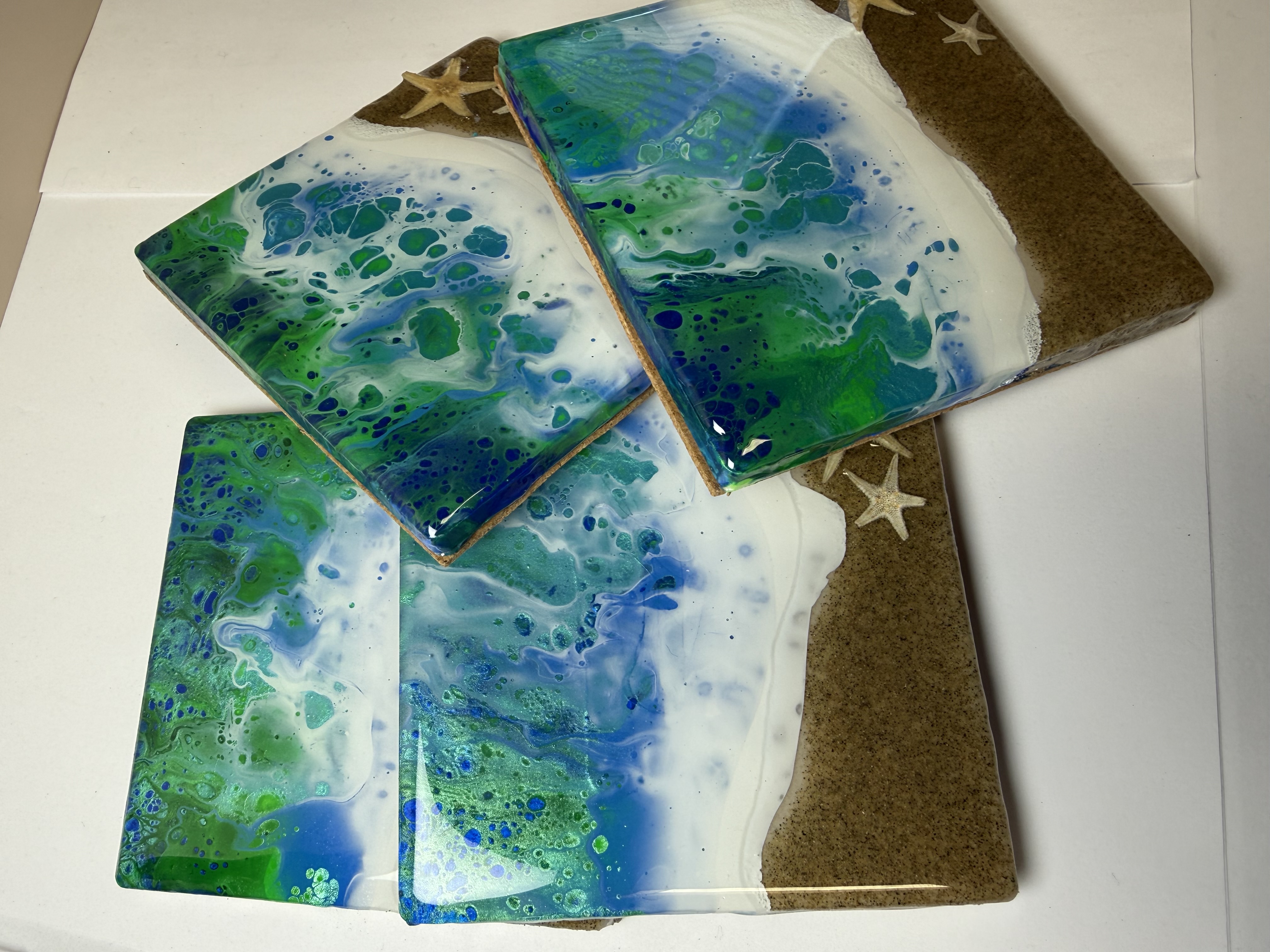 Blue and green ocean-wave artwork with sandy shores and starfish