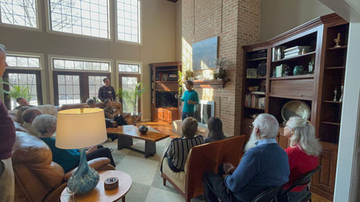 Ranjan speaking to a crowd of people in a bright living room
