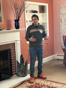 Ranjan speaking in front of a living room fireplace
