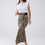 Thumbnail: Woman wearing white top and leopard print skirt, posing confidently on white background.