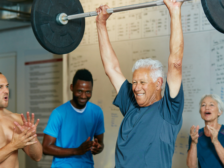 Elderly man lifting heavy weights with a group