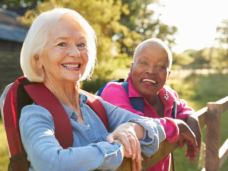 two senior women posing on a fence while hiking