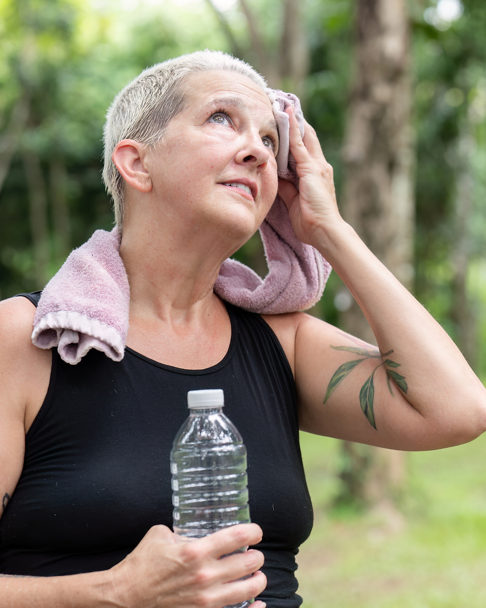 Senior women wiping her brow after doing cardio outside