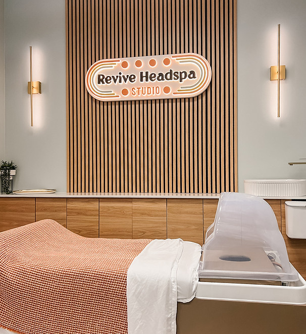 Interior of Revive Headspa Studio in Denver, featuring a modern spa bed with an orange blanket, soft lighting, and a wood-acc