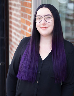 Sarah Buckingham, headspa technician at Revive Headspa Studio in Denver, smiling confidently in a black blouse with long, str