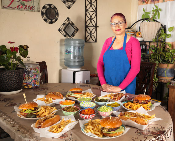 Dolores the Owner of Los Dogos Del Gordo with a table full of her Sonora style food.