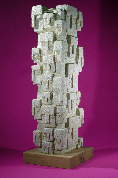 Les gens est une sculpture en pierre de Beaulieu posée sur un socle en bois