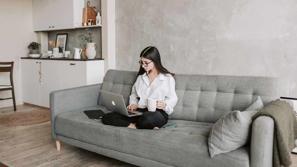 Woman on video call with laptop demonstrating an Alcohol Rehab Alternative, seated at home on gray couch.