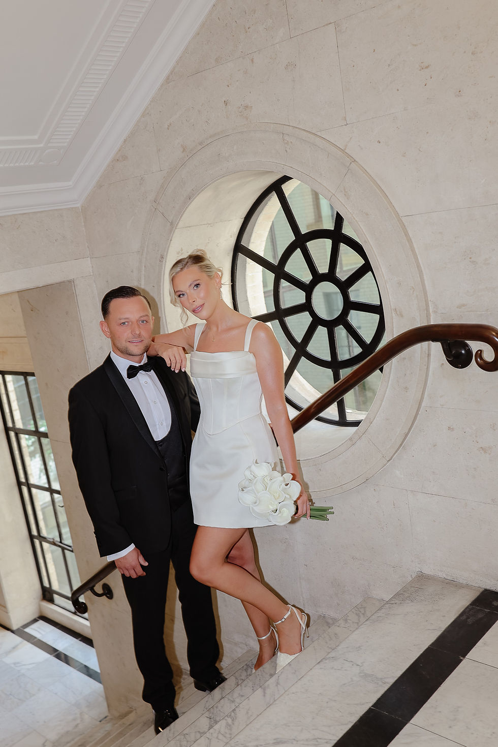 Bride in corseted mini dress with groom on the staircase landing at Old Marylebone Town Hall