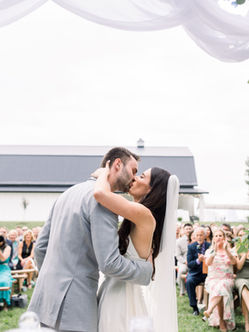 Bride and groom just pronounced man and wife, kissing under the arbor at StoneBriar Farm. Photo by The Grays Photography