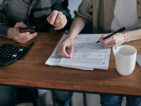 Hands filling out paper documents on a desk