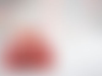 Three wrapped Christmas gifts on a white foreground with lights in the distance in the background.