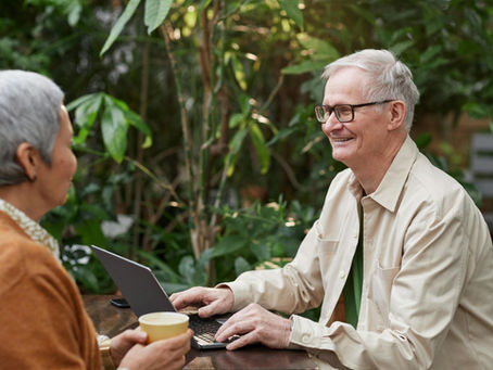 Two adults looking over a computer while enjoying coffee.