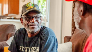A person wearing a Veterans hat in conversation with someone out of the frame. 