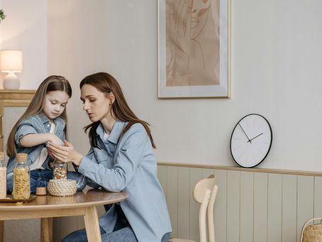 A mom and daughter counting beans in a jar, with a clock and painting behind them.