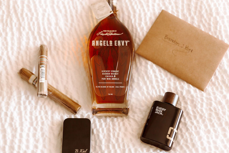Groom wedding day detail flat lay with cologne, liquor bottle and letter from the bride.