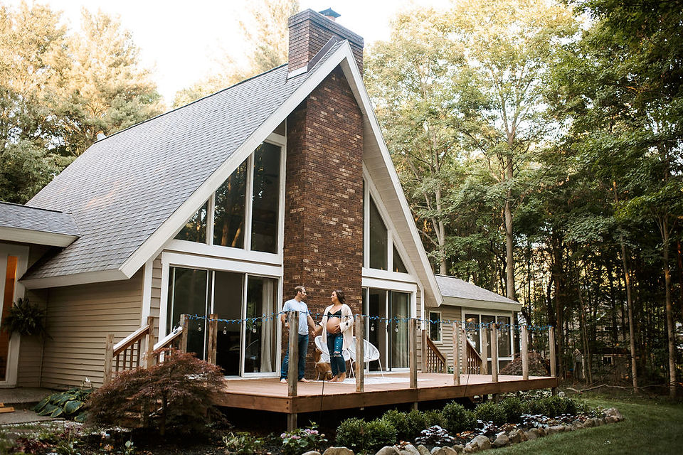 Couple standing on their back porch in Michigan for their maternity photoshoot.